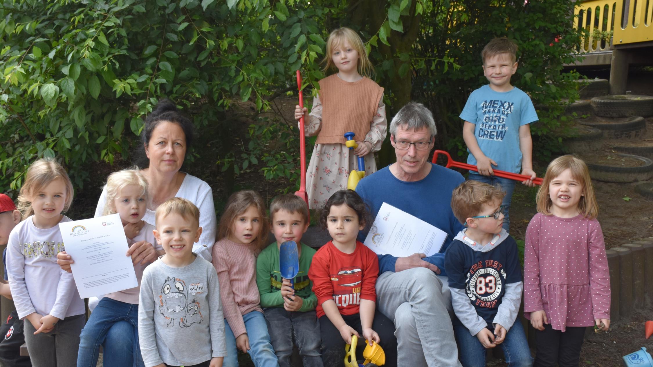 Birgit Hüsing-Hackfort (Familienzentrum), Dieter Homann (Caritas-Beratungsstelle) und Kinder aus dem Familienzentrum 'Zum Regenbogenland'.