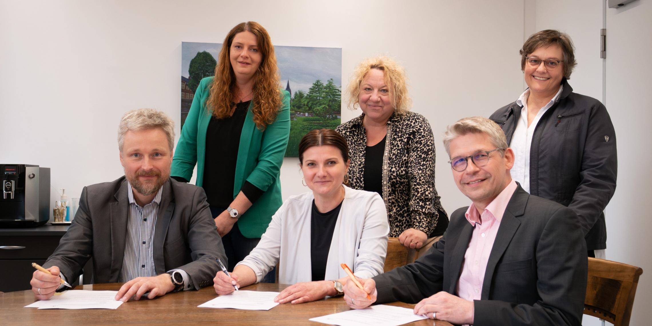 Bei der Vertragsunterzeichnung (sitzend v.l.) Timo Plaß (Sozialdienst katholischer Frauen für die Dekanate Ahaus und Vreden), Marina Bänke (Stadt Ahaus) und Peter Schwack (Caritas-Vorstand) gemeinsam mit (v.l.) Claudia Mersmann, Silke Herbrand und Vera Reimer.