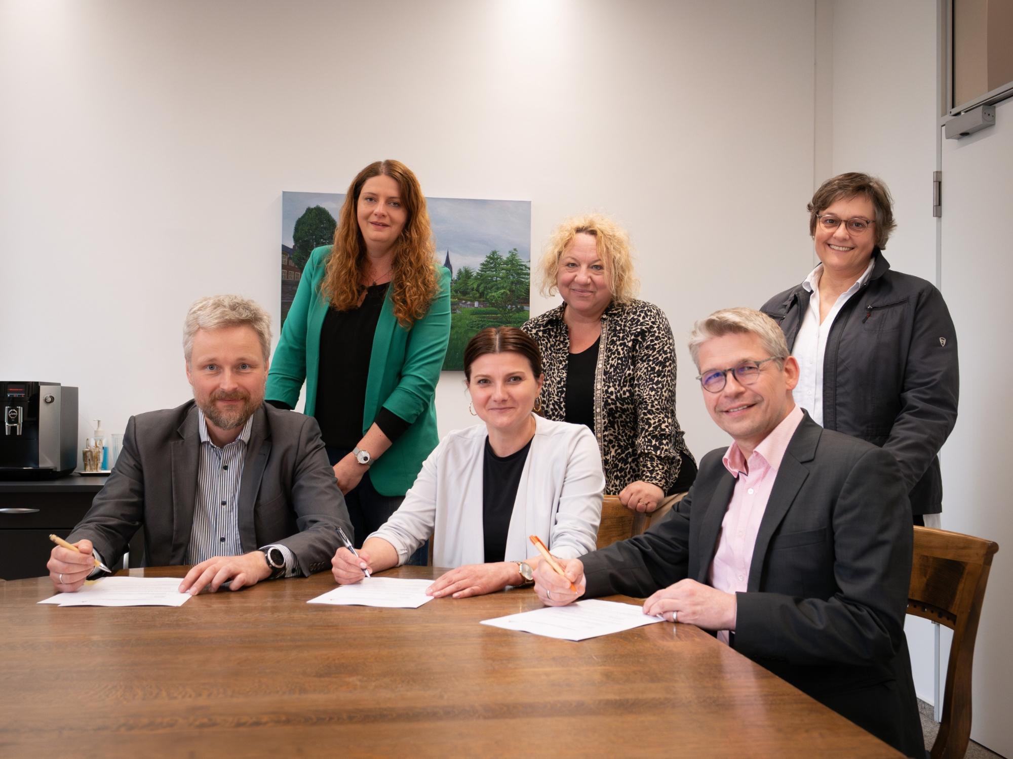 Bei der Vertragsunterzeichnung (sitzend v.l.) Timo Plaß (Sozialdienst katholischer Frauen für die Dekanate Ahaus und Vreden), Marina Bänke (Stadt Ahaus) und Peter Schwack (Caritas-Vorstand) gemeinsam mit (v.l.) Claudia Mersmann, Silke Herbrand und Vera Reimer.