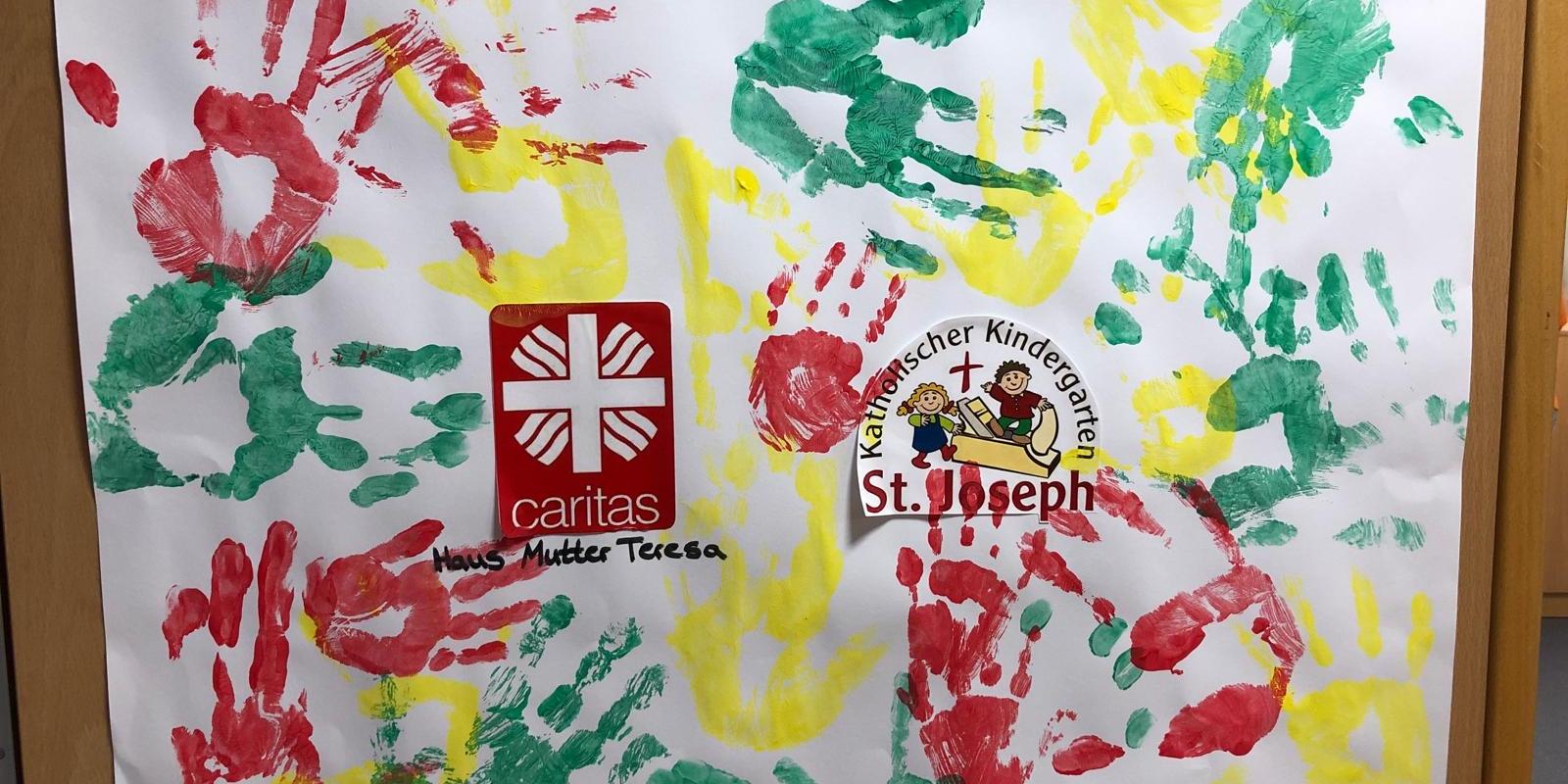Rote, grüne und gelbe Handabdrücke der Tagesgäste auf einem Plakat.