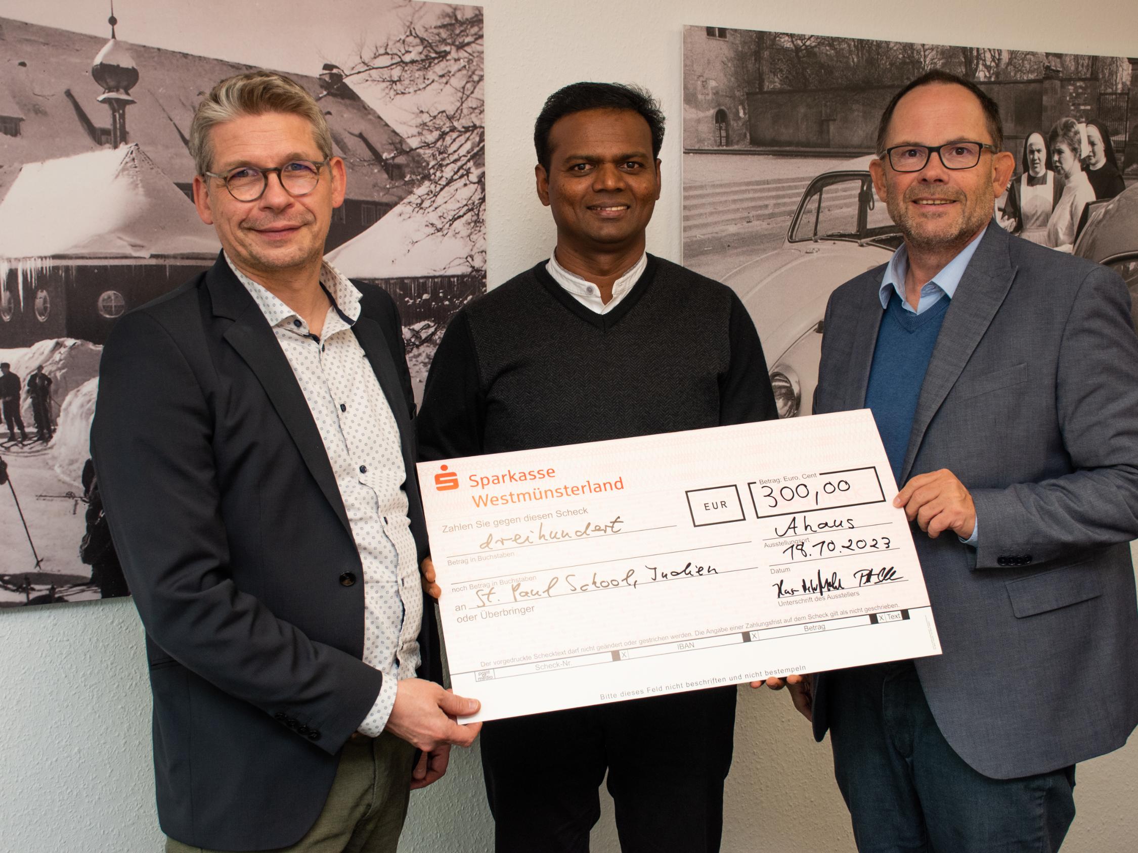Die Vorstände Peter Schwack (l.) und Hans-Peter Merzbach (r.) überreichten einen symbolischen Scheck an Pater Raju Peter.