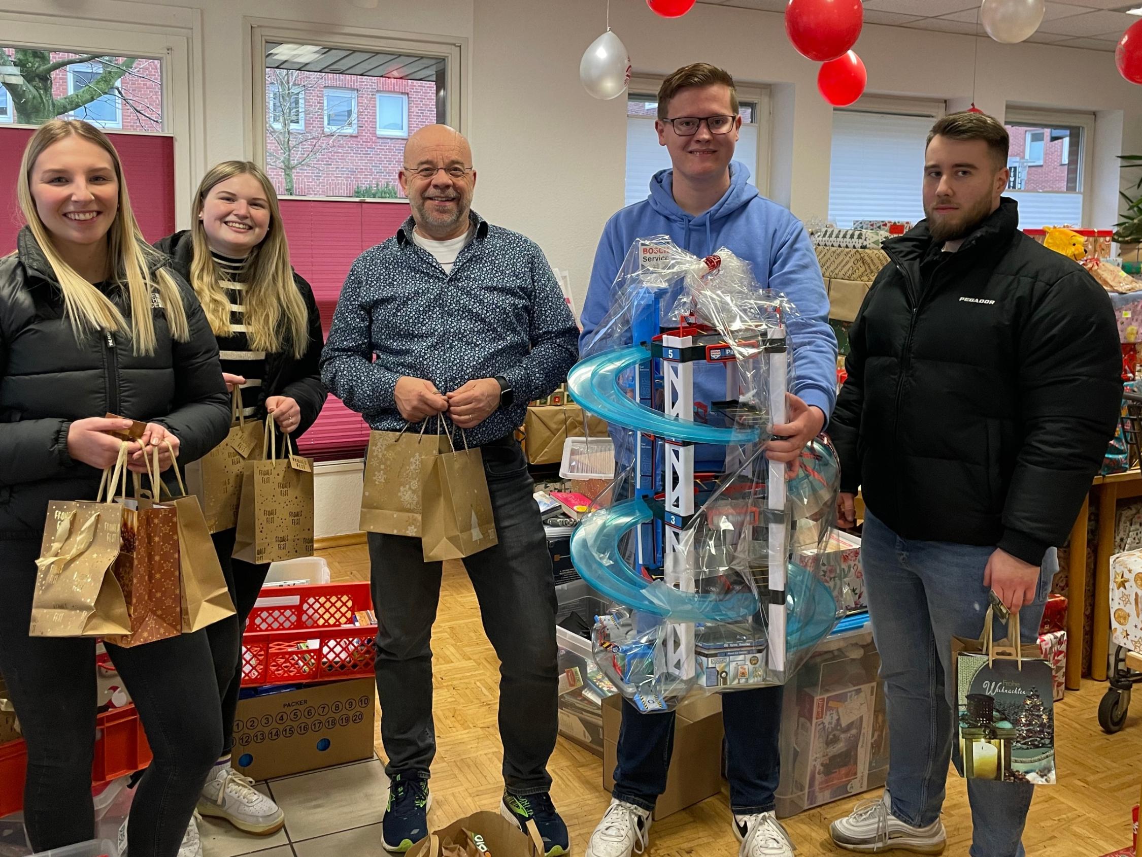 Johannes Lügering (M.) von der Ahauser Tafel  und die Auszubildenden Johanna Büscher, Alessia Bone, Nils Gieseler und Szabolcs Tamas (v.l.) bei der Übergabe der Weihnachtspäckchen.