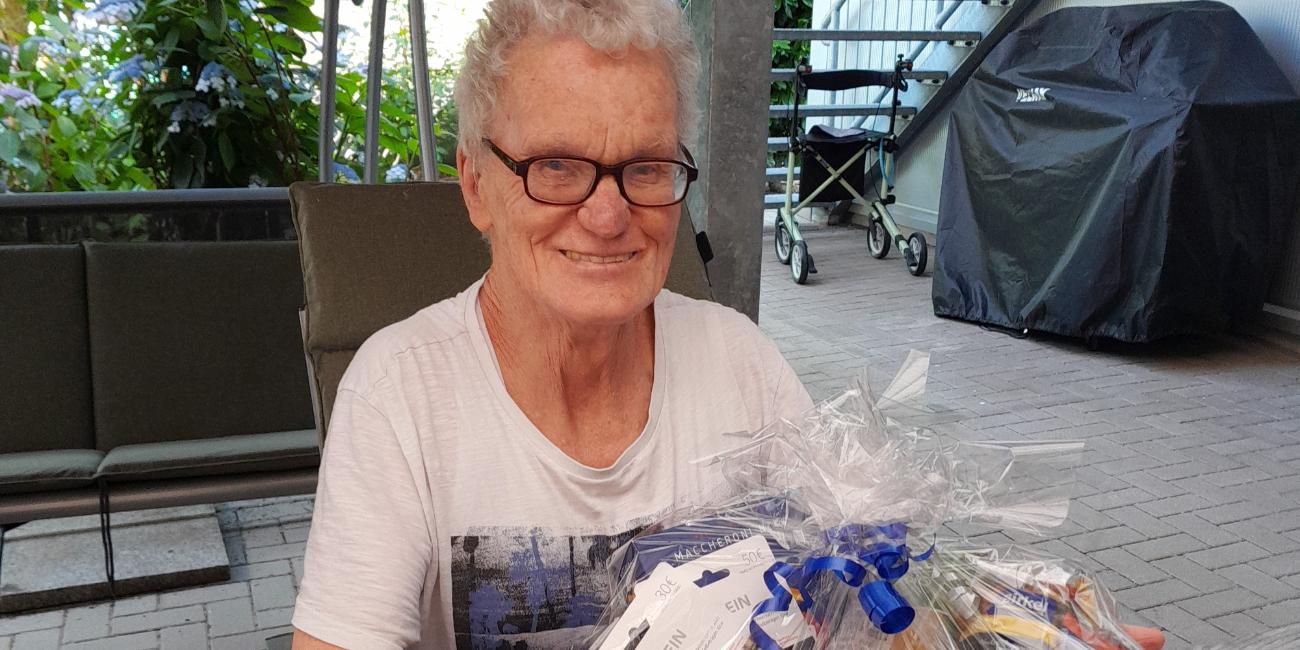 Peter Maas präsentiert einen Präsentkorb, der gefüllt ist mit Leckereien.