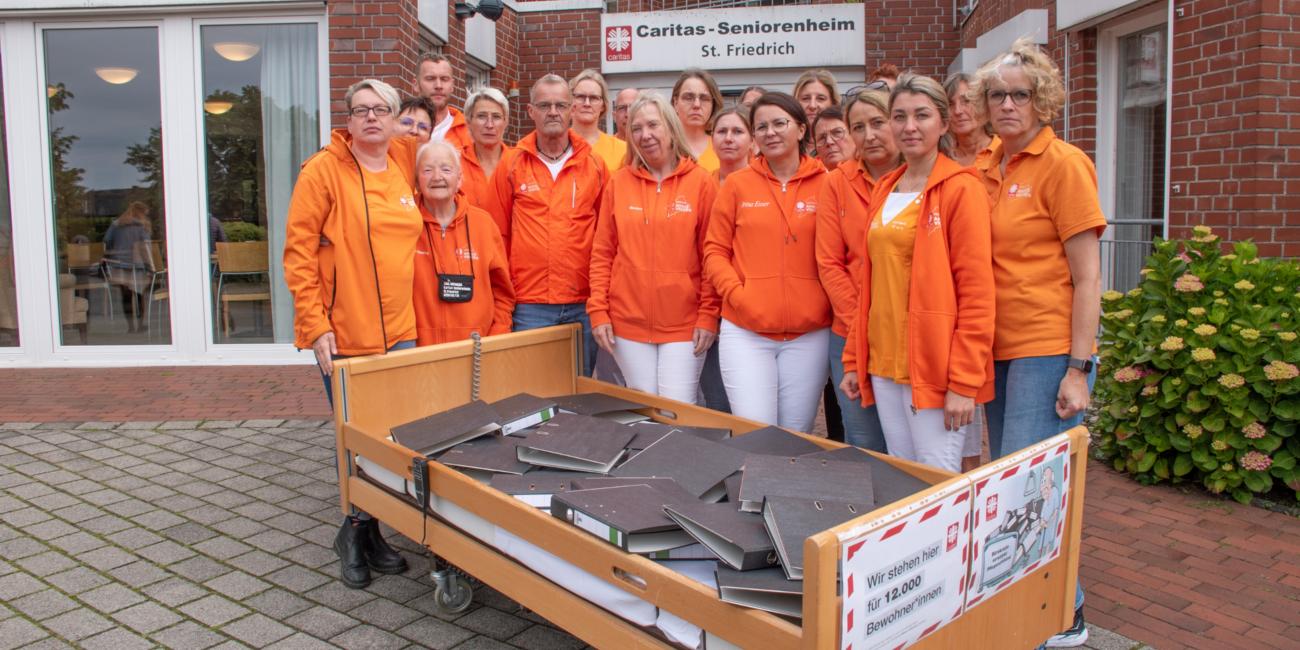 Ein Pflegebett voller Aktenordner – mit dieser Aktion vor dem Seniorenheim St. Friedrich und anderen Einrichtungen weist der Caritasverband Ahaus-Vreden auf den Verhandlungs- und Bearbeitungsstau beim Landschaftsverband Westfalen-Lippe hin.