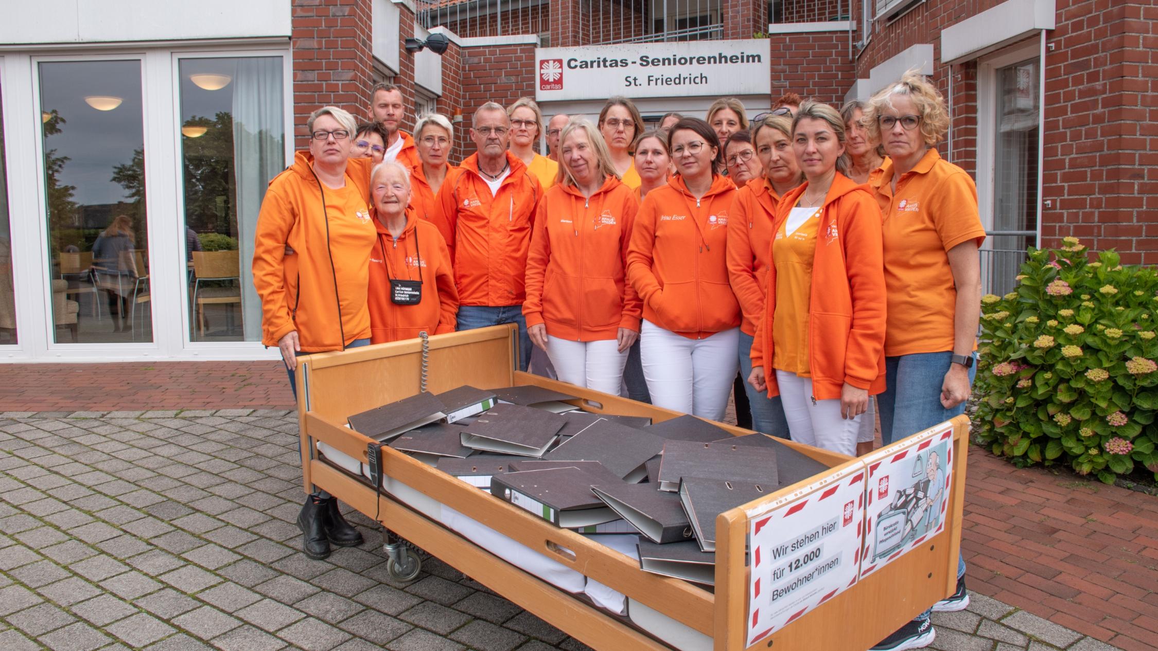 Ein Pflegebett voller Aktenordner – mit dieser Aktion vor dem Seniorenheim St. Friedrich und anderen Einrichtungen weist der Caritasverband Ahaus-Vreden auf den Verhandlungs- und Bearbeitungsstau beim Landschaftsverband Westfalen-Lippe hin.