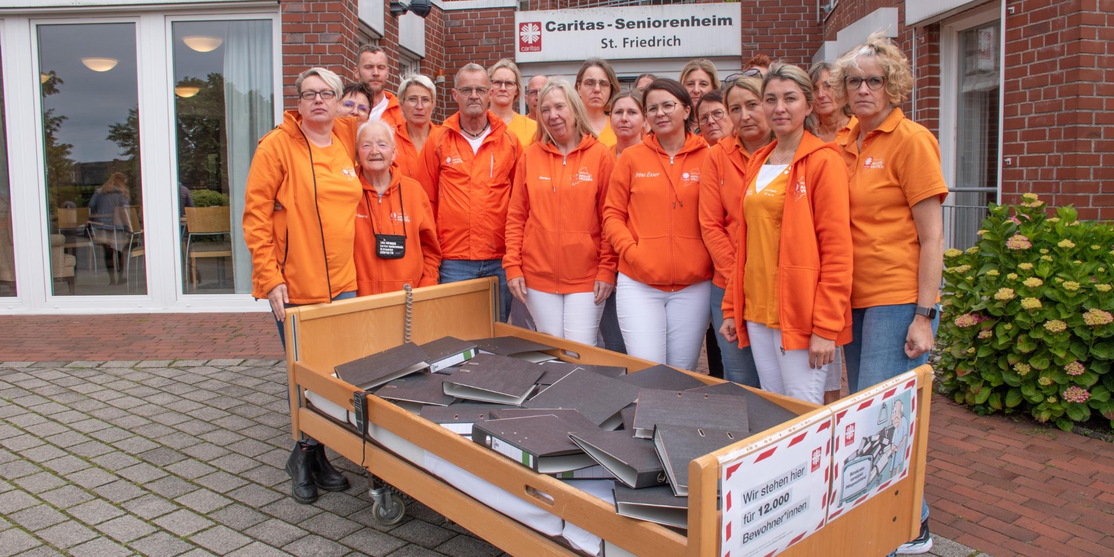 Ein Pflegebett voller Aktenordner – mit dieser Aktion vor dem Seniorenheim St. Friedrich und anderen Einrichtungen weist der Caritasverband Ahaus-Vreden auf den Verhandlungs- und Bearbeitungsstau beim Landschaftsverband Westfalen-Lippe hin.