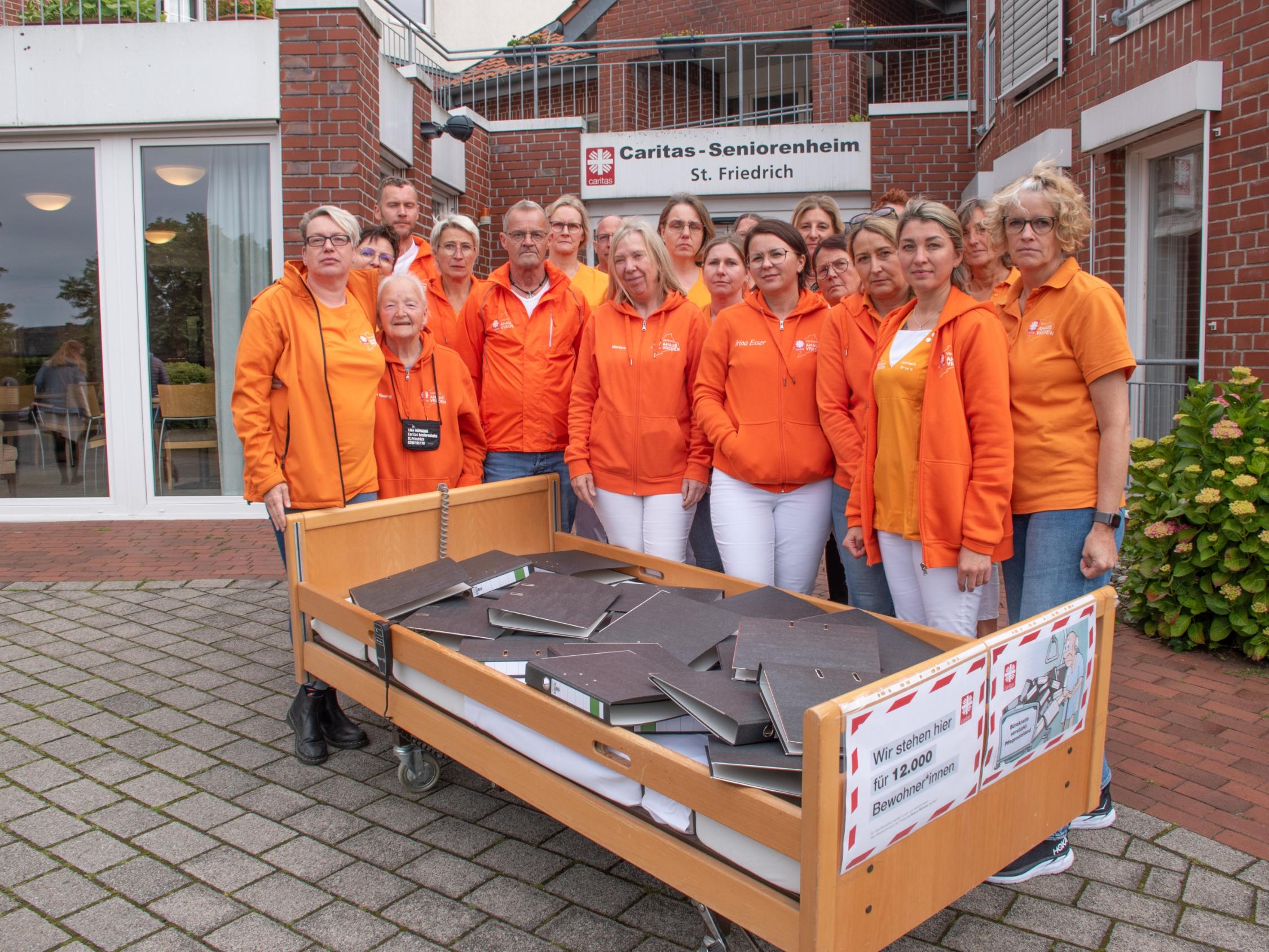 Ein Pflegebett voller Aktenordner – mit dieser Aktion vor dem Seniorenheim St. Friedrich und anderen Einrichtungen weist der Caritasverband Ahaus-Vreden auf den Verhandlungs- und Bearbeitungsstau beim Landschaftsverband Westfalen-Lippe hin.