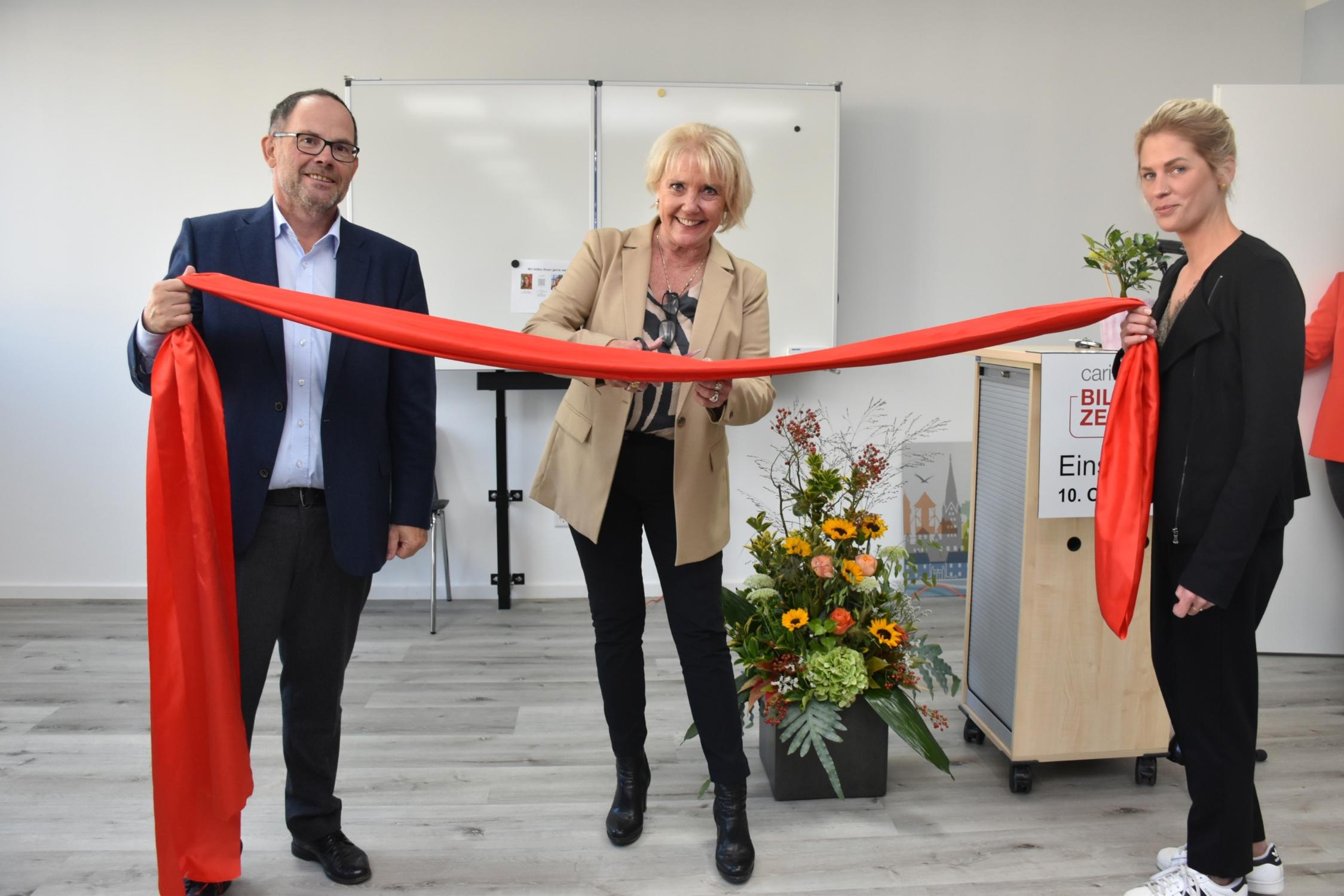 Symbolischer Schnitt durchs Eröffnungsband: Schulleiterin Petra Berger (M.), assistiert von Bildungswerk-Geschäftsführer Hans-Peter Merzbach und einer Kollegin aus dem Team des CBZ Rheine.